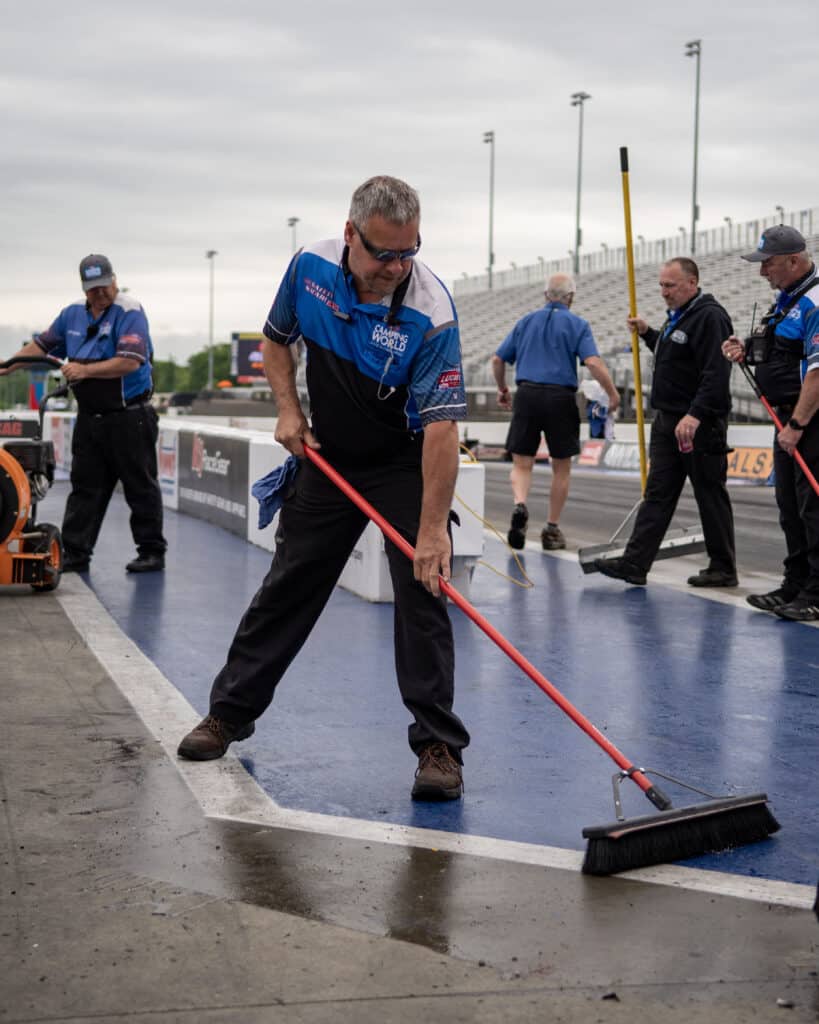 workers at zmax dragway clean and prepare the track for the next race