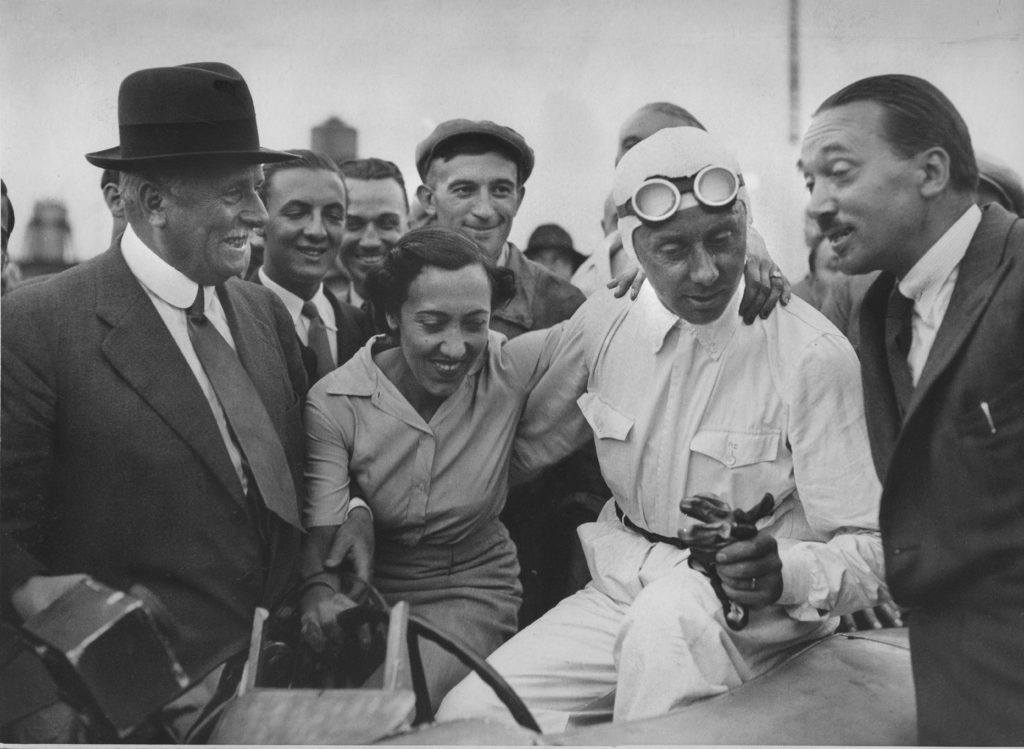 Rene Dreyfus claims the prize on August of 1937. Left to right: Charles Weiffenbach, Chou-Chou, Rene Dreyfus, and Jean Francois. From Faster by Neal Bascomb, published Houghton Mifflin Harcourt.