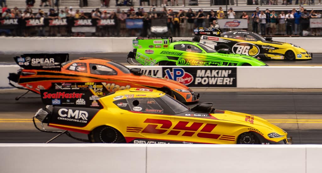 four nhra drag racing cars in motion at zmax speedway in a four-wide race